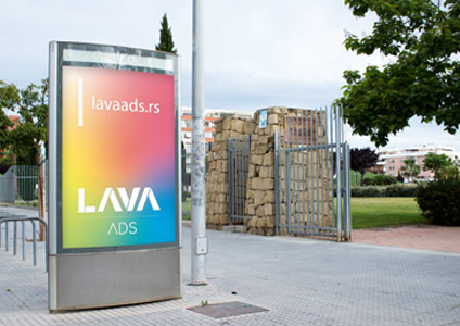 LED bilbord na ulici, kraj ulaza, sa reklamom za Lava ADS u duginim bojama.